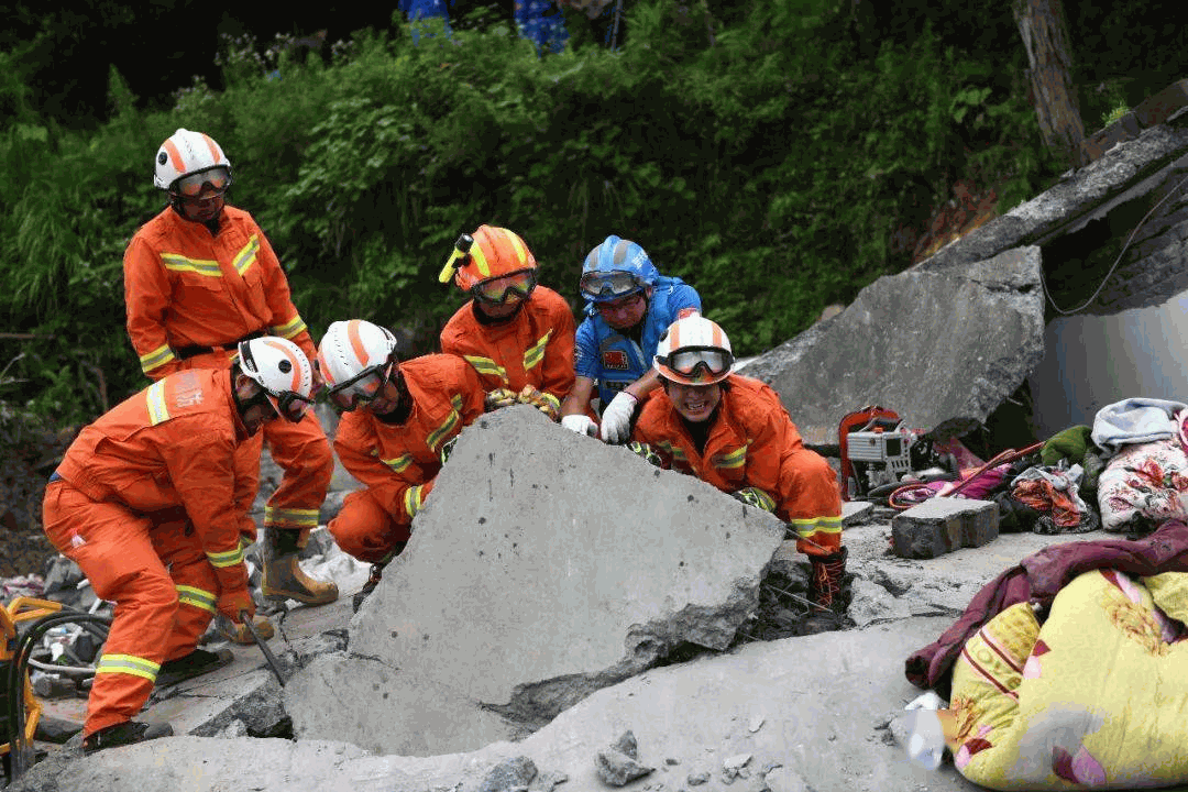Rescue workers in orange uniforms carrying a portable power generator