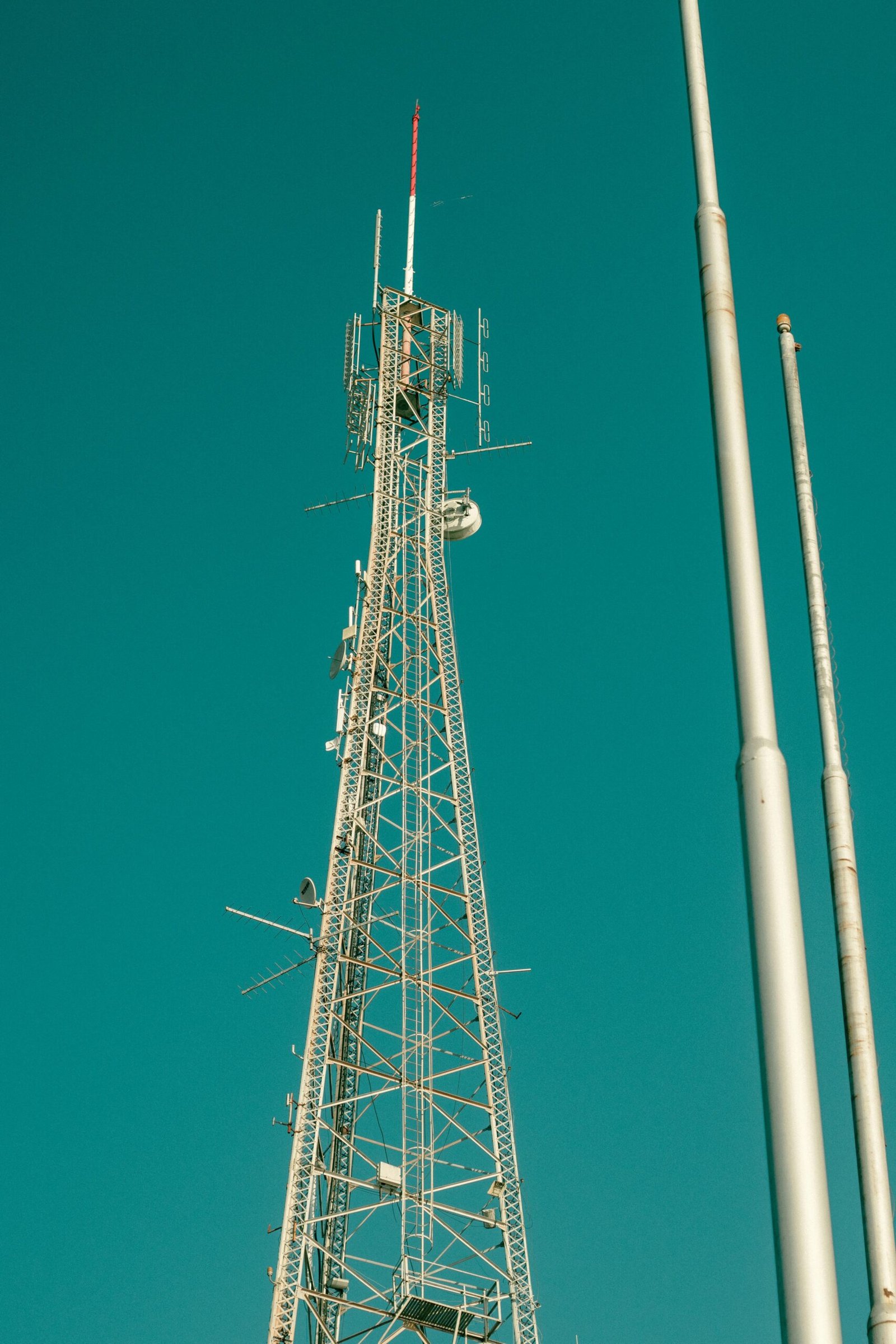 Steel lattice telecommunications tower against a teal sky